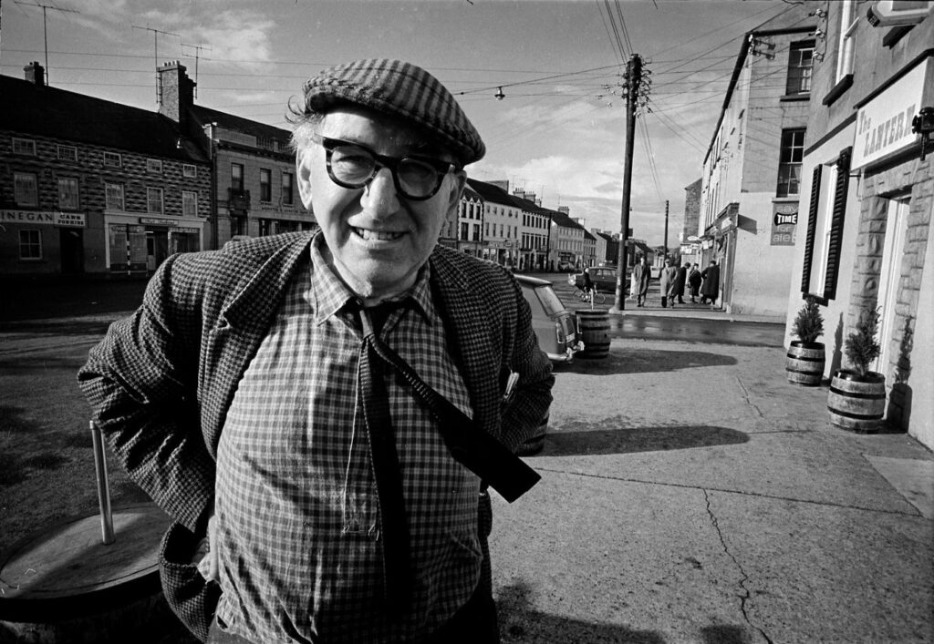Fig 1. Patrick Kavanagh, Main Street, Carrickmacross mid 1960s with O’Hanlon’s newsagents in the background. Photograph courtesy of National Library Ireland, taken by Colman Doyle